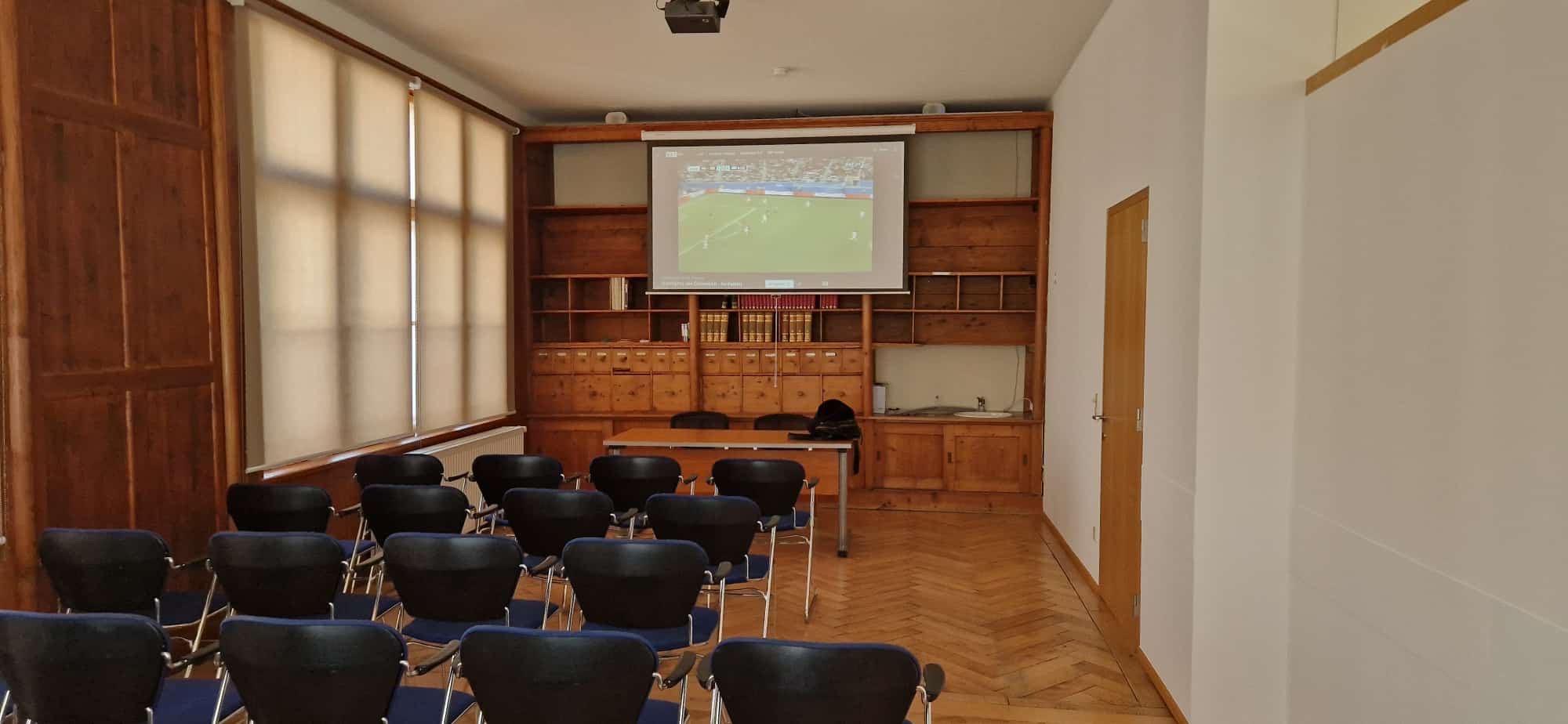 Der Seminarraum mit Bestuhlung, Leinwand und Fischgrätparkett